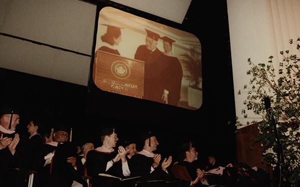 people at a graduation watching a video screen